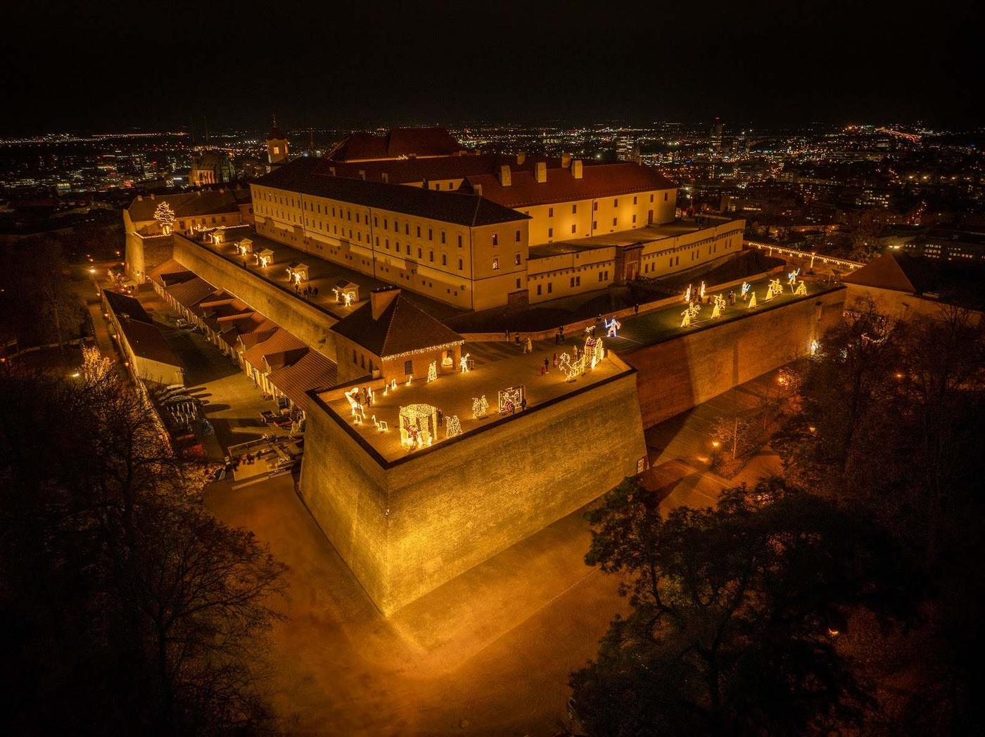 Noční letecký pohled na hrad Špilberk s rozsvícenými světelnými instalacemi na hradbách